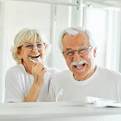 Altes Ehepaar putzt gemeinsam Zähne im Bad und hat Spaß