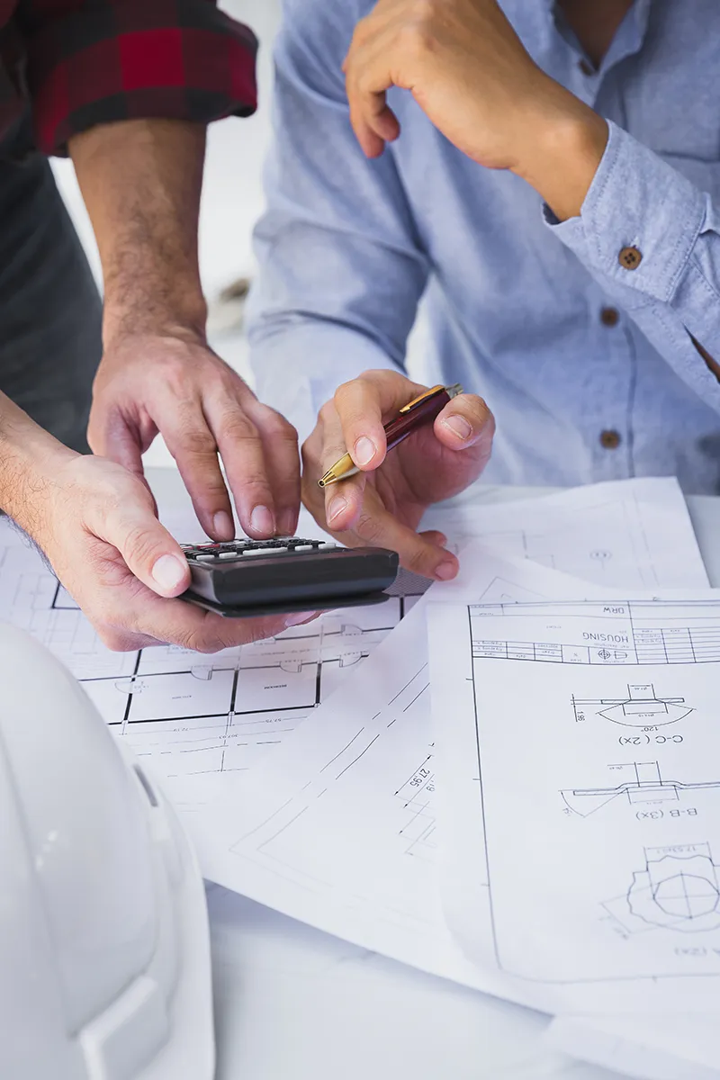 Symbolbild Nahaufname von 2 Leuten vor Plänen, der Mann hält ein Telefon in der Hand