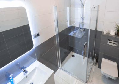 modernes Badezimmer mit beleuchtetem Spiegel, Glasdusche und WC